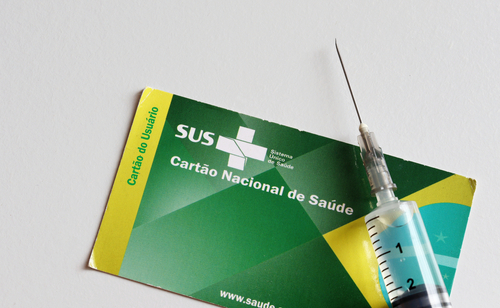 Vaccine syringe over the Brazilian national public health card (the SUS)