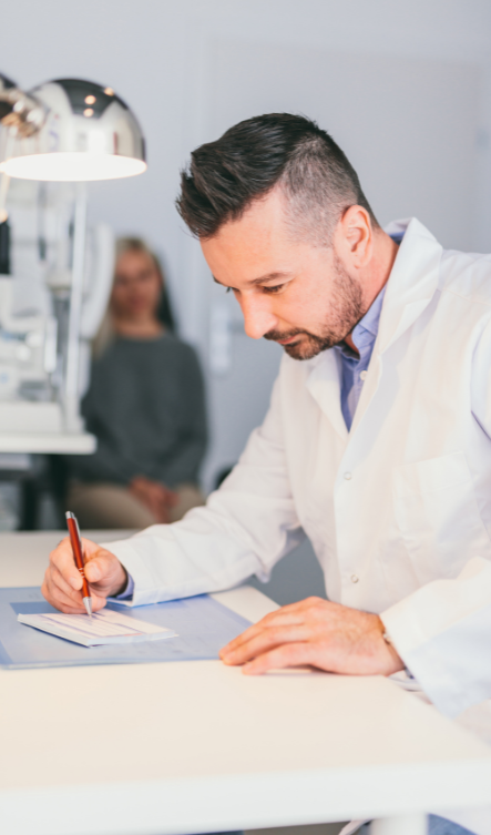Man in white coat writing on a perscription pag