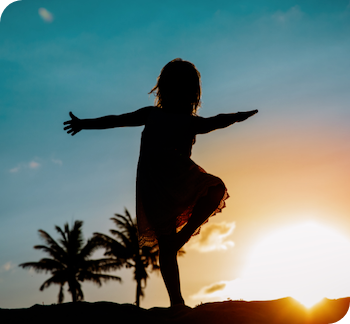 Child's silhouette against the setting sun and palm trees